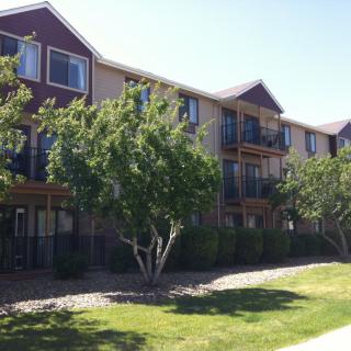 A sunny view of a residential apartment building surrounded by greenery.