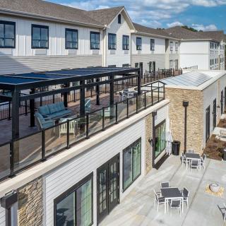 A modern residential building with outdoor seating and a glass-railed patio.