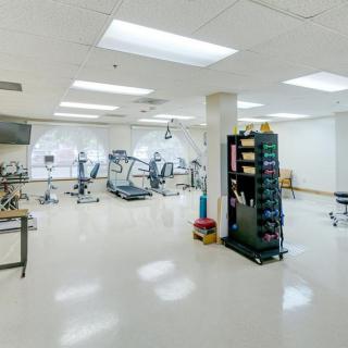 A spacious physical therapy room equipped with various exercise machines and rehabilitation tools.