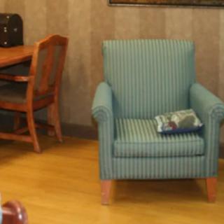 A cozy interior with a striped armchair and a wooden desk in the background.