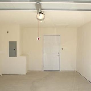 An empty garage with a door and a ceiling light fixture.