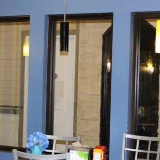 A small seating area with a table and chairs, set against a blue wall with large windows.