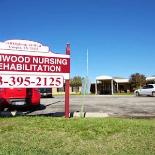 An exterior view of the Elmwood Nursing Rehabilitation facility with a prominent sign.