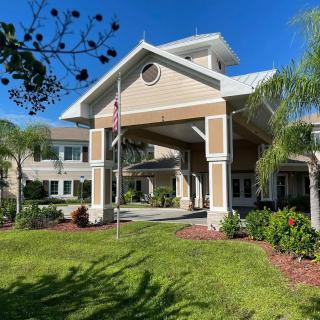 A sunny view of a residential building with a landscaped entrance and palm trees.