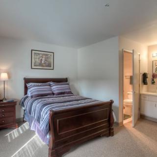 A cozy bedroom with a wooden bed, striped bedding, and an adjoining bathroom.