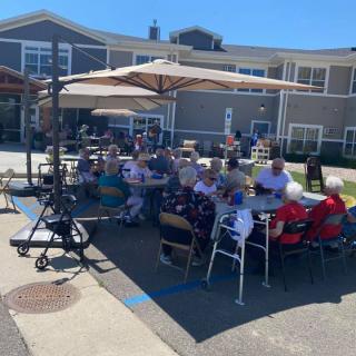 A group of people enjoying an outdoor gathering under umbrellas on a sunny day.