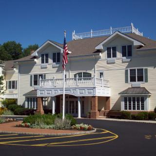 A large residential-style building with a central entrance and an American flag in front.