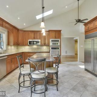 A spacious kitchen with modern wooden cabinets and a central island with dining chairs.
