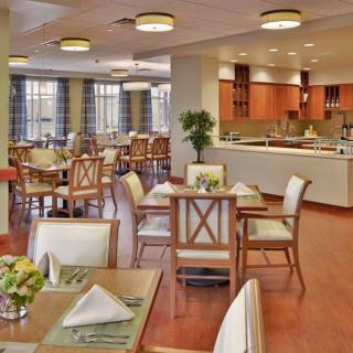 A beautifully arranged dining area with neatly set tables and chairs, featuring warm lighting and modern decor.