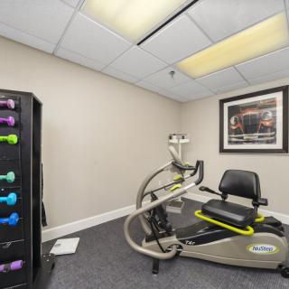 A small exercise room featuring a stationary bike and a rack of dumbbells.
