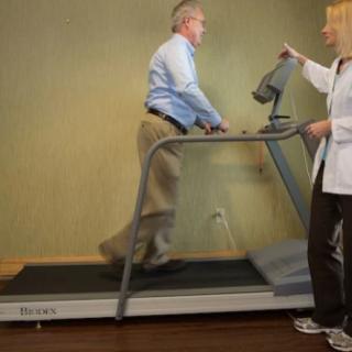 A healthcare professional is assisting a patient on a treadmill.