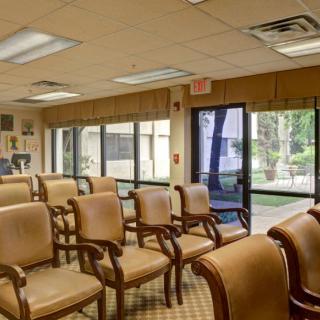 A well-lit waiting room with rows of chairs and large windows looking outside.