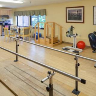 A physical therapy room equipped with parallel bars and various rehabilitation equipment.