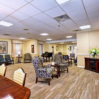 A spacious and well-decorated lounge area with various seating options, a piano, and elegant decor.