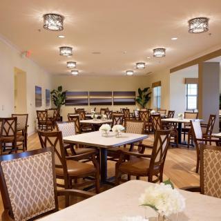 A spacious dining room with elegantly arranged tables and chairs, featuring modern lighting fixtures.