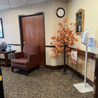 A cozy waiting area featuring a comfortable chair, decorative elements, and a wall clock.