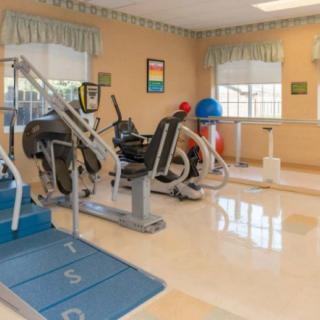 A well-lit gym with various exercise equipment and workout machines.