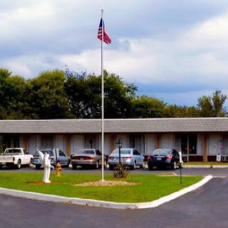 A view of a building with an American flag, surrounded by vehicles in the parking lot.