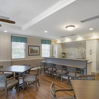 A modern dining area featuring multiple tables and chairs, with elegant lighting and wood flooring.