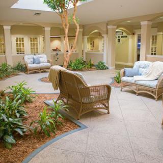 A cozy indoor garden lounge with wicker furniture and surrounding plants.