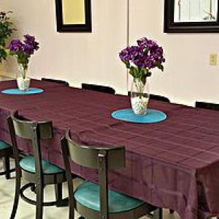 A dining area with a maroon tablecloth, decorated with vases of purple flowers.