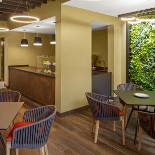 A modern cafe interior featuring stylish furniture and a green vertical wall.