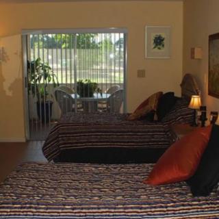 A cozy bedroom with two beds and a view of a patio through the window.