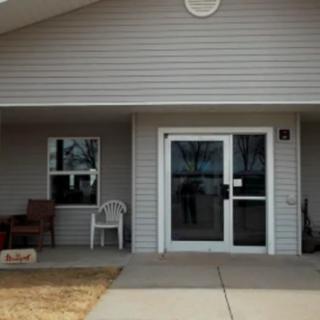 A house entrance with a porch, including a door, window, and chairs.