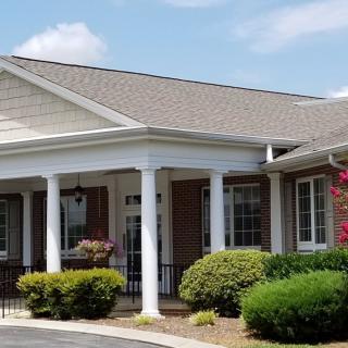 A residential building with a porch and landscaped surroundings.