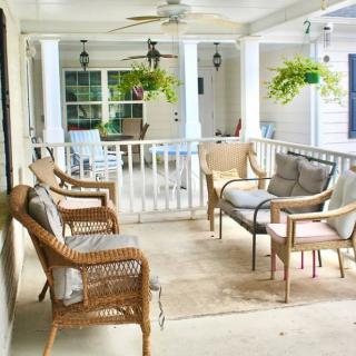 A cozy porch with wicker furniture, hanging plants, and a ceiling fan.