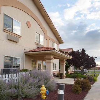 A modern motel exterior with a landscaped entrance under a cloudy sky.