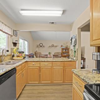 A spacious kitchen with wooden cabinets, granite countertops, and modern appliances in an open-concept design.