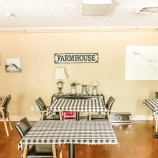 A cozy farmhouse-style cafe interior with checkered tablecloths and warm lighting.