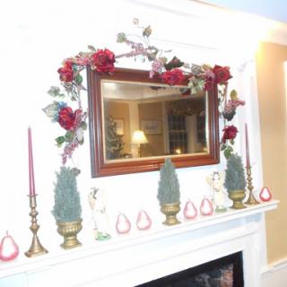 A beautifully decorated fireplace mantel with a mirror, holiday candles, and festive greenery.