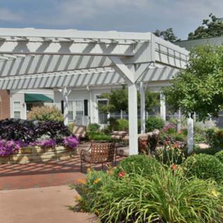 A beautifully landscaped garden featuring a white pergola and vibrant flowers.