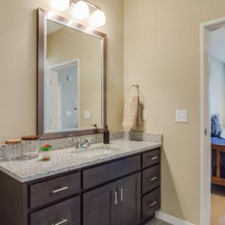 A modern bathroom with a dark wood vanity and large mirror.