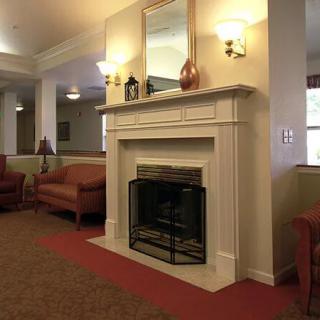 A cozy living room interior featuring a white fireplace surrounded by comfortable seating and warm lighting.