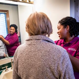A woman receives personal care in a cozy bathroom setting, highlighting a moment of connection and support.