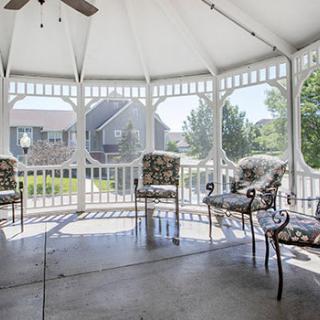 A spacious gazebo with elegant patio furniture, offering a serene garden view.