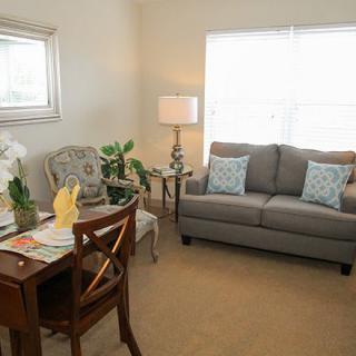 A cozy living room with a sofa, chairs, and a small desk with decorative plants.