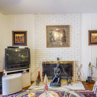 A cozy living room with a vintage TV and a brick fireplace adorned with artwork and sculptures.