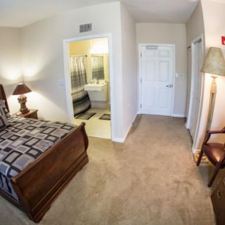 A cozy bedroom with a bed, lamp, and an adjoining bathroom.