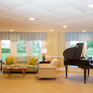 A cozy living room featuring a grand piano and comfortable seating arrangements.