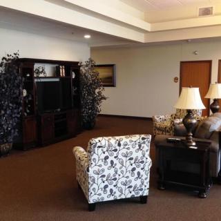 A cozy living room with a patterned chair, sofas, lamps, and a television.