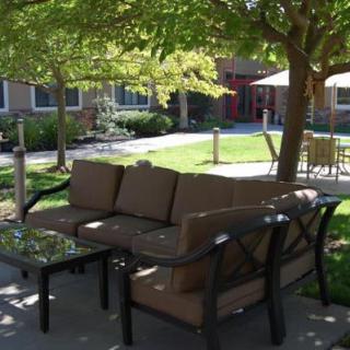 A cozy outdoor patio area with comfortable seating and shaded by trees.
