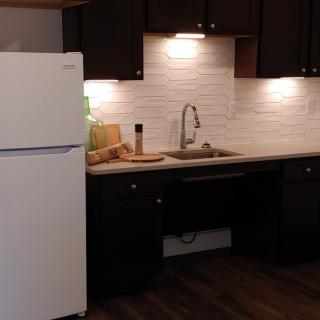 A modern kitchen with dark cabinets, a white refrigerator, and a tiled backsplash.