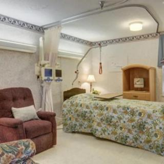 A hospital room featuring a bed, medical equipment, and a comfortable recliner chair for patient care.