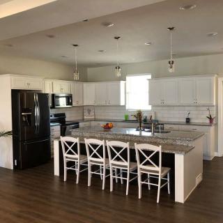 A modern kitchen with white cabinets, a central island, and wooden bar stools.