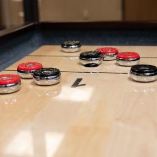 A close-up view of a shuffleboard table with pucks in play.