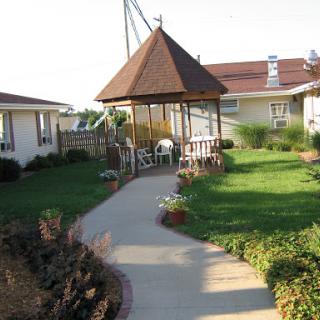 A serene garden with a gazebo and a winding pathway, surrounded by greenery and flowers.